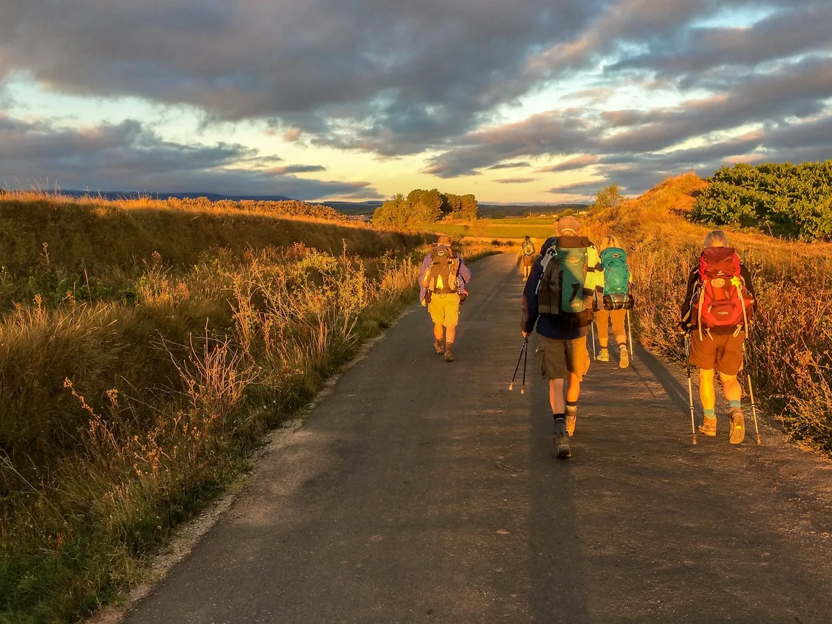 A group of pilgrims walking down a road on the Camino
